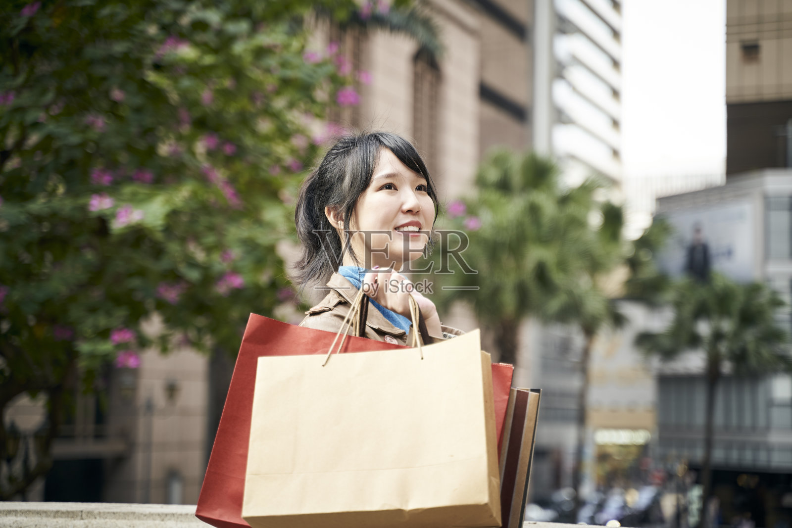 年轻的亚洲女人拿着购物袋走在街上照片摄影图片