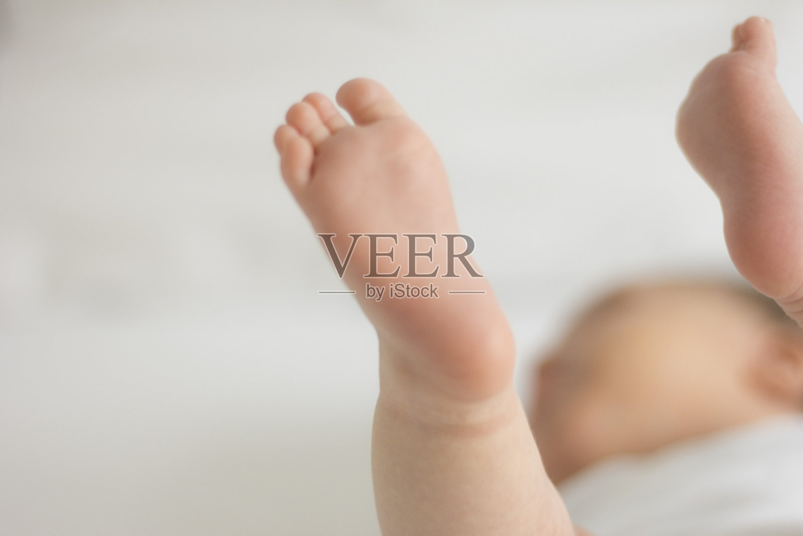 一个新生婴儿的腿躺在白色的床上照片摄影图片