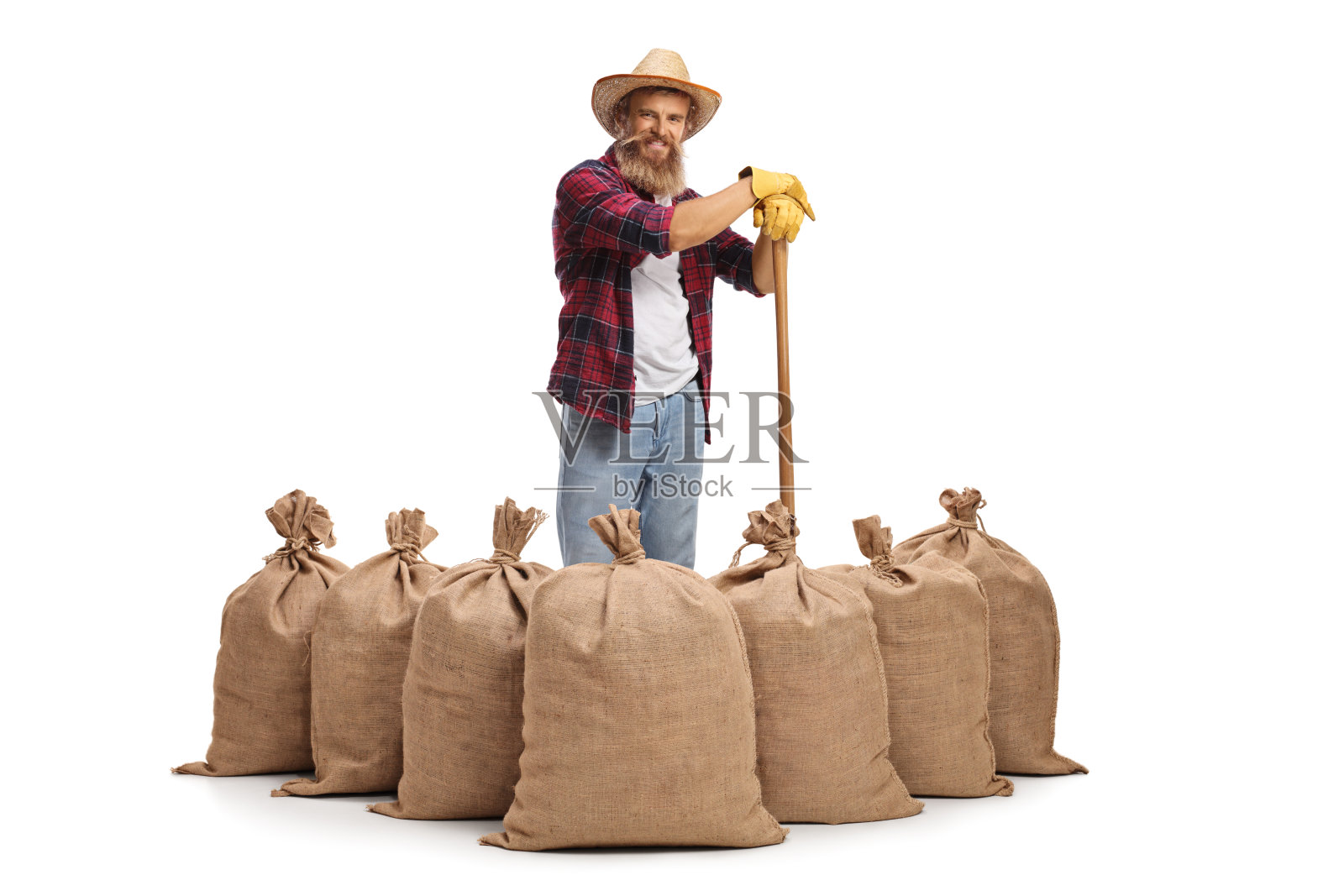 一个戴着草帽的农民，靠在麻袋后面的铲子上照片摄影图片