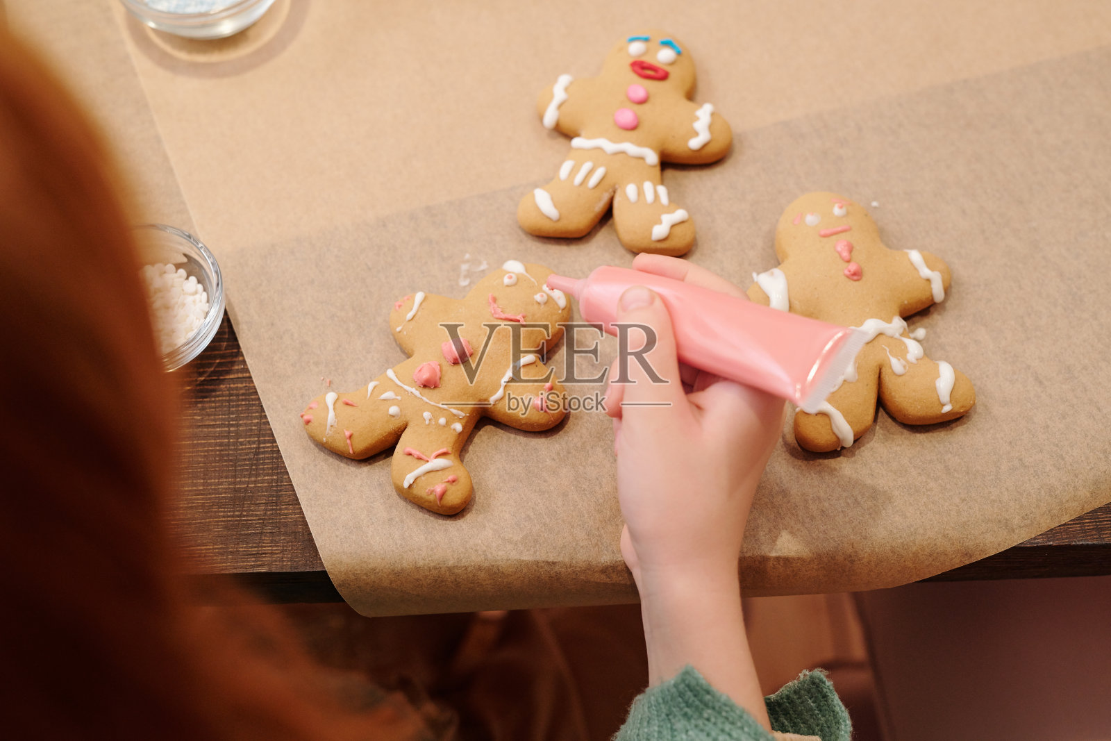 小女孩的手用粉红色的釉面装饰自制的姜饼照片摄影图片