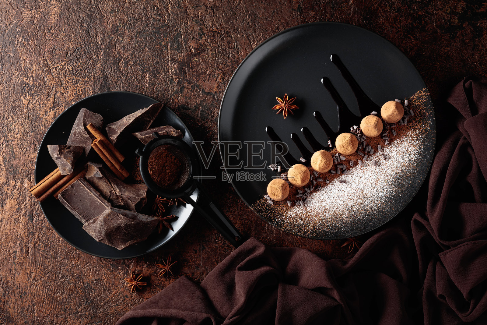 黑色盘子上的松露巧克力配巧克力酱。照片摄影图片