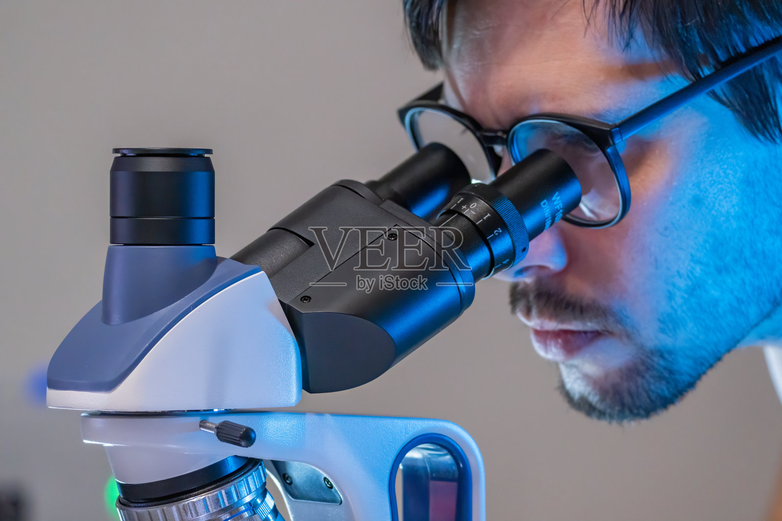 实验室里的年轻科学家正在显微镜里观察。微生物的概念。照片摄影图片