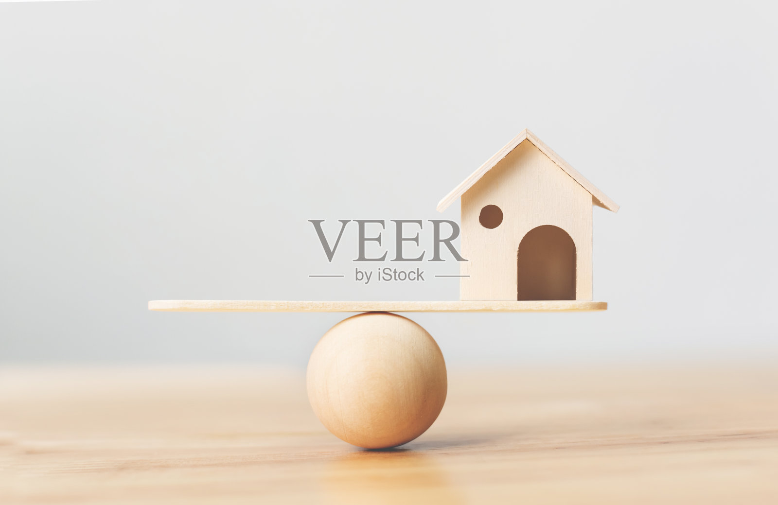 木制房屋上的木秤跷跷板。房地产投资和房屋抵押金融房地产概念照片摄影图片