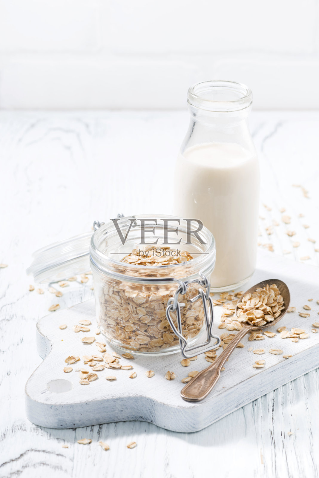 燕麦片和一瓶牛奶在白色的木制背景上，垂直照片摄影图片