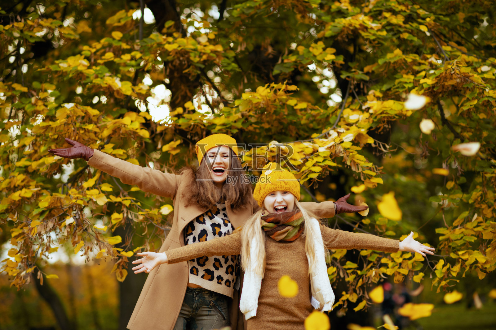 快乐的母亲和孩子在秋天的城市公园外欢腾照片摄影图片