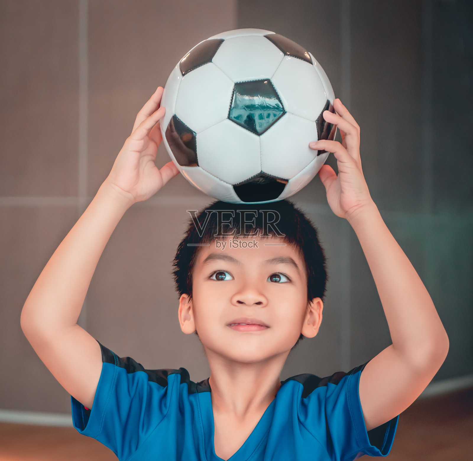 肖像足球亚洲男孩拿着足球在他的头上为青年运动概念。照片摄影图片
