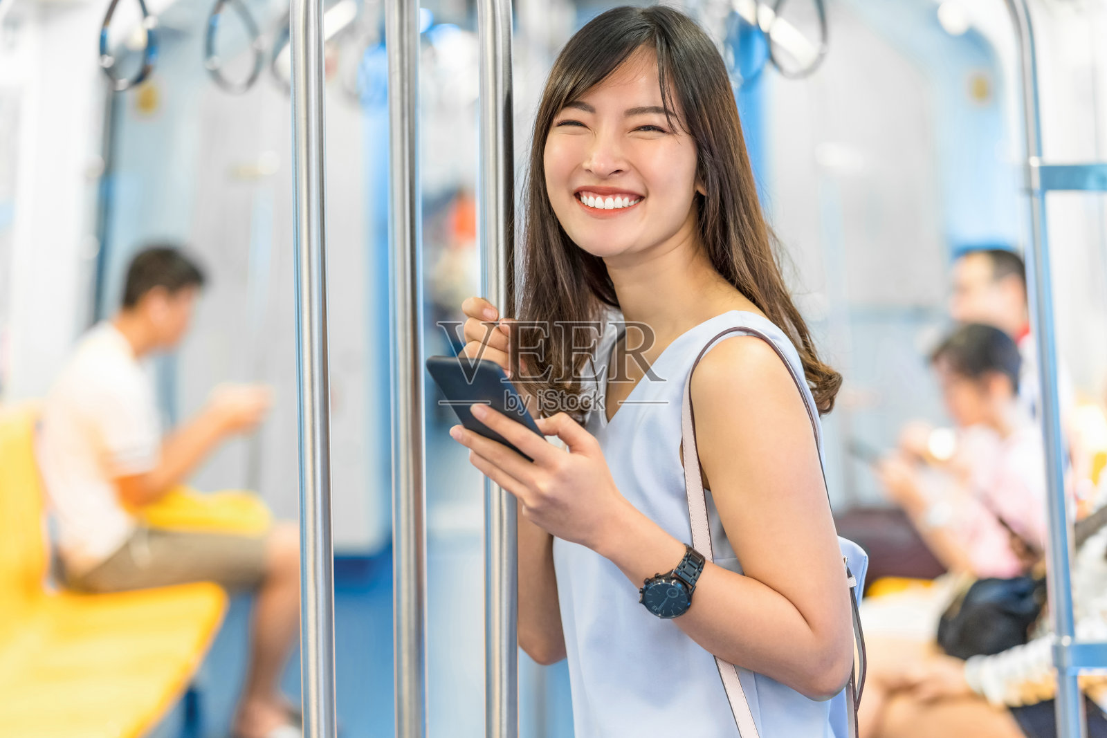 年轻的亚洲女性乘客在地铁列车上通过智能手机使用社交网络，在大城市旅行时，日本，中国，韩国的生活方式和日常生活，通勤和交通理念照片摄影图片