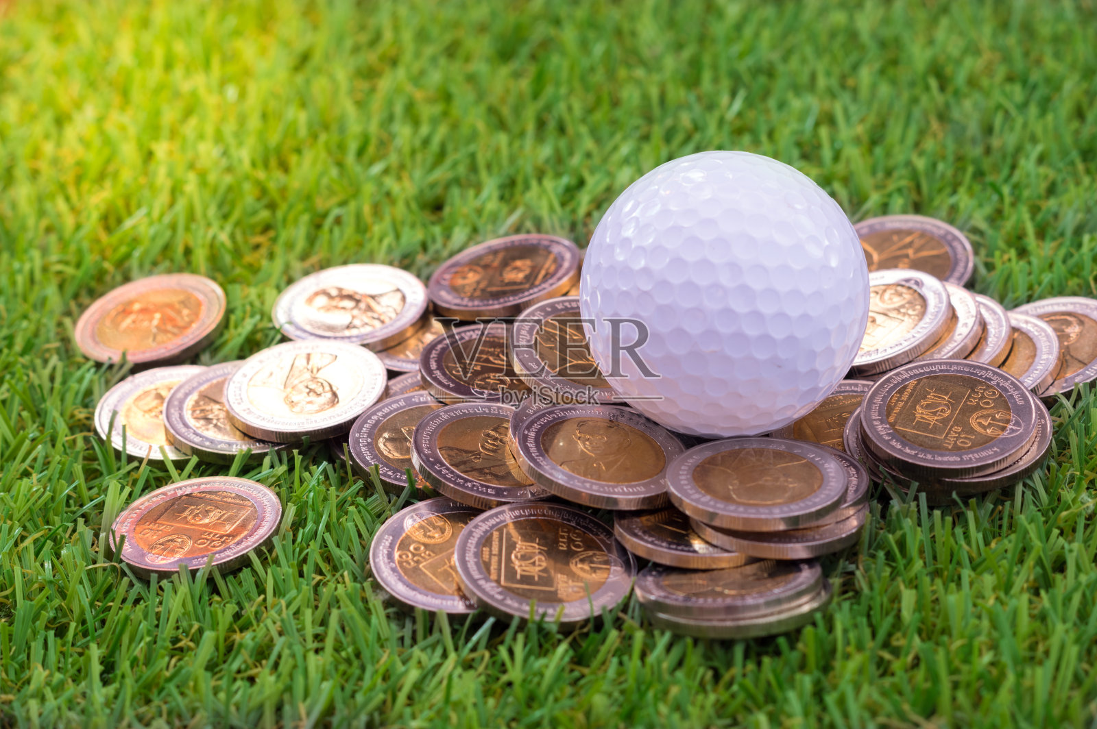 绿色草地上镶有金币的高尔夫球。照片摄影图片