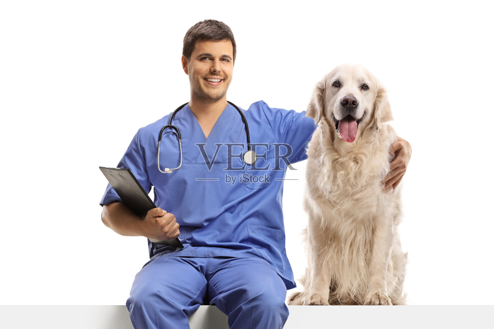 一名身穿蓝色制服的兽医坐在一块白色的嵌板上，抱着一只寻回犬照片摄影图片