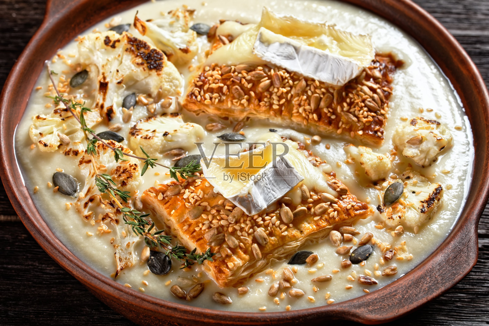 奶油素食花椰菜汤，上面是土制木桌上的陶土碗里融化的卡芒贝尔奶酪烤面包，上面是水平视野，近景，法式美食照片摄影图片