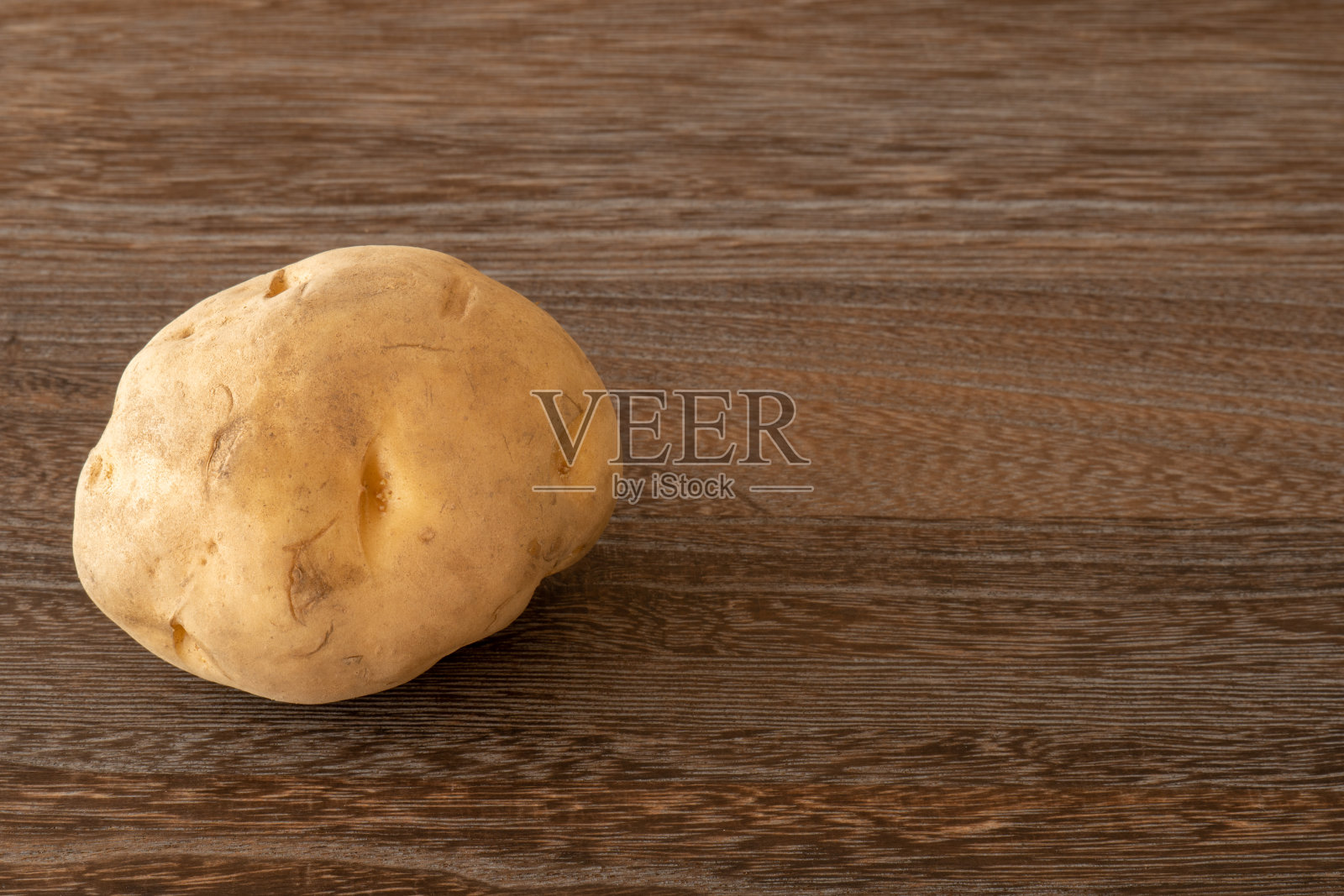 一个土豆放在深褐色的木桌上照片摄影图片