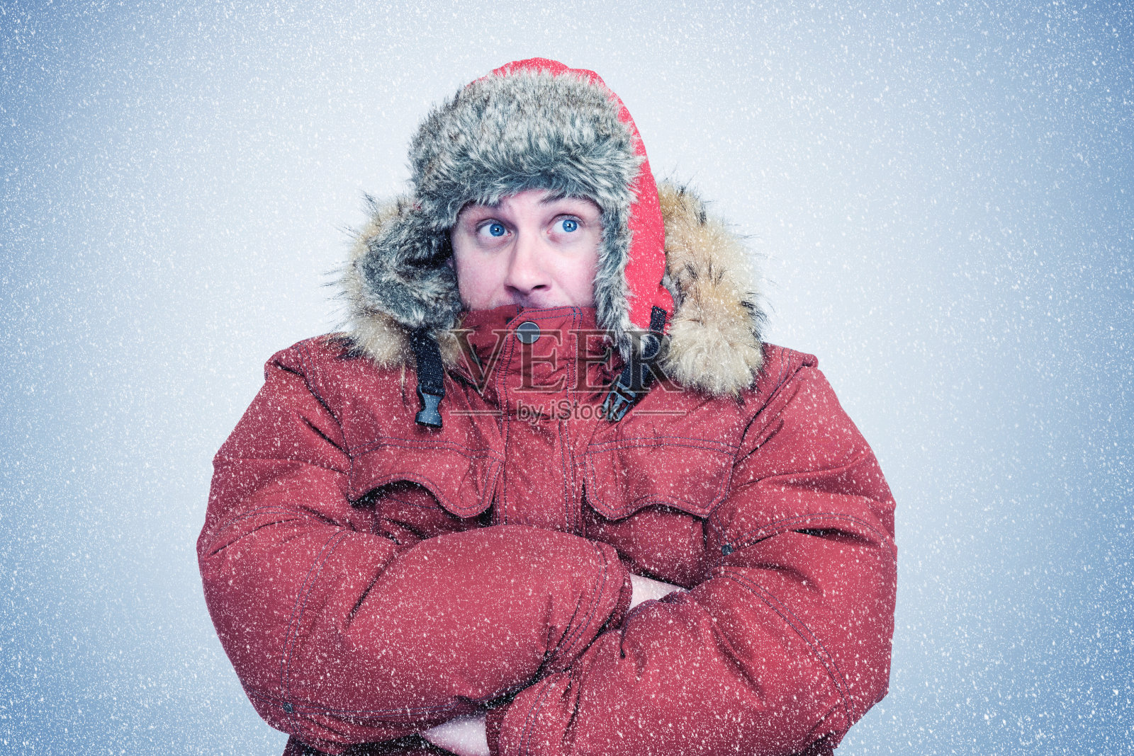 一个穿着红色冬衣的冻僵的人站在雪地里暖手，周围是雪，一场暴风雪照片摄影图片