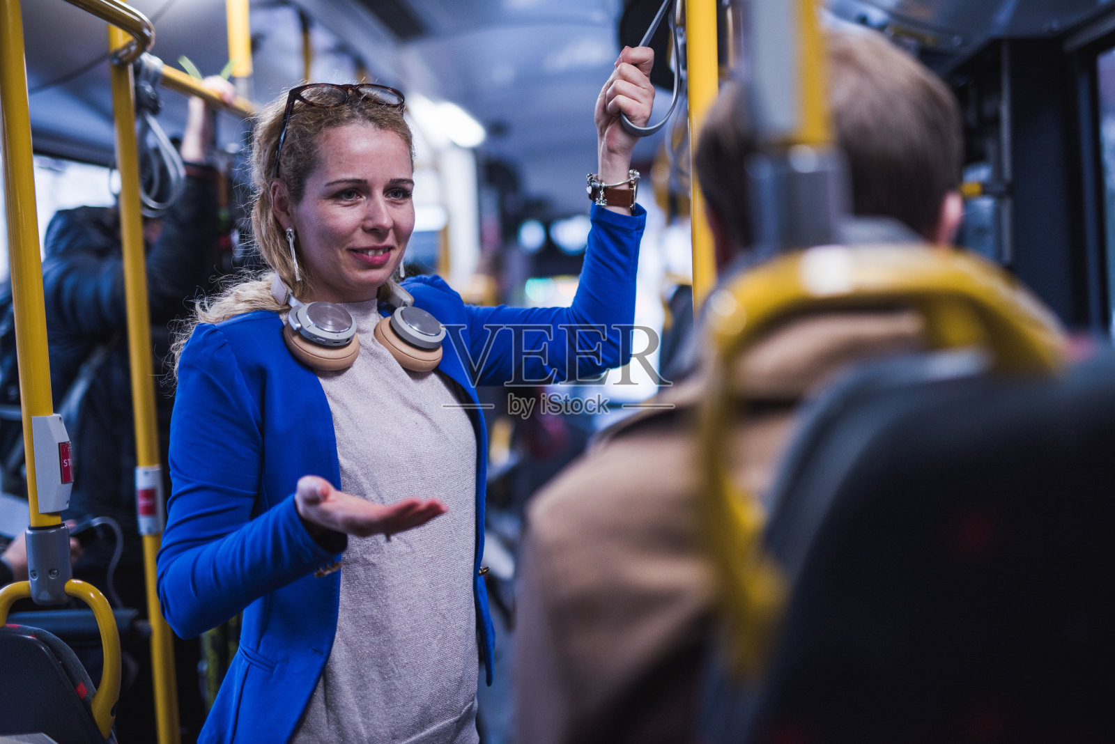 金发女人在公车上和朋友聊天。照片摄影图片