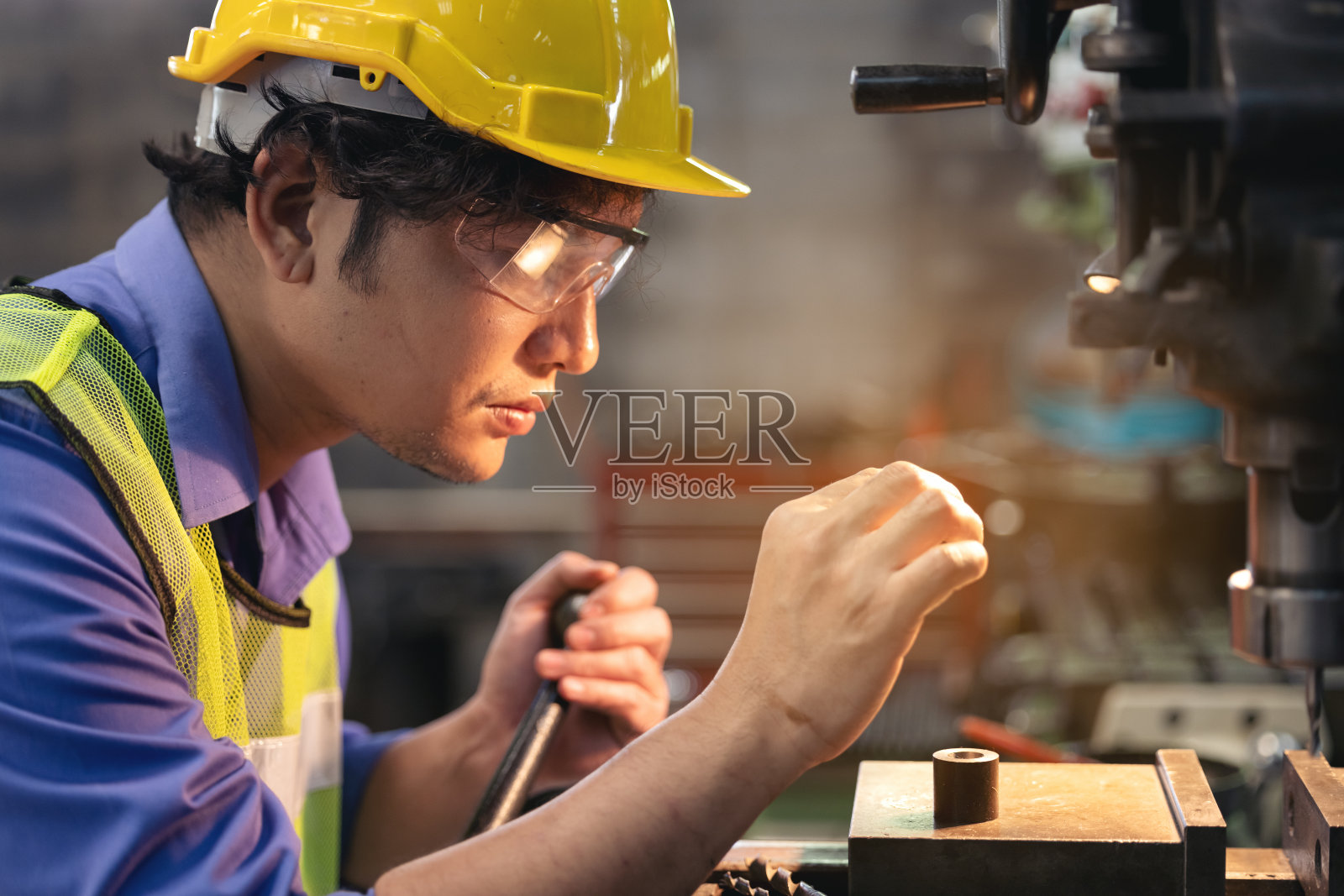 一个戴眼镜的工人站在工业设备附近验证生产。工人在工厂里操作机器照片摄影图片