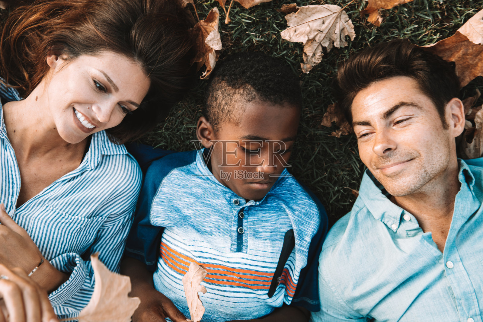 年轻的家庭躺在公园的草地上休息照片摄影图片
