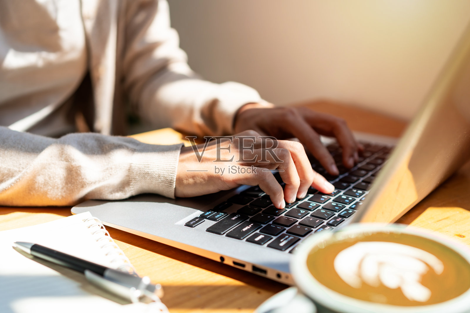 年轻女子拿着一杯咖啡坐在咖啡店里用笔记本电脑工作照片摄影图片
