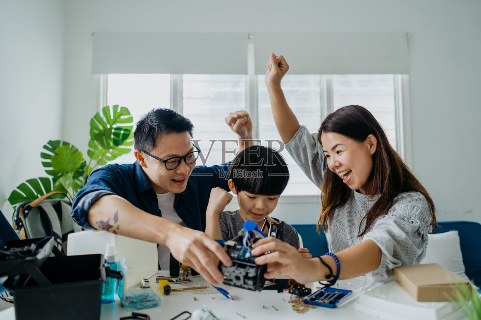 亚洲华人家庭在家里一起建造机器人玩具照片摄影图片