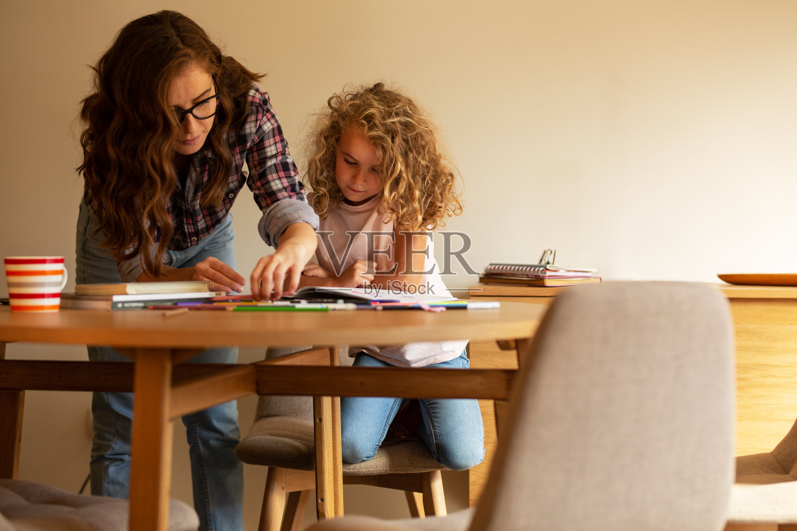 母亲帮助女儿完成家庭作业。照片摄影图片