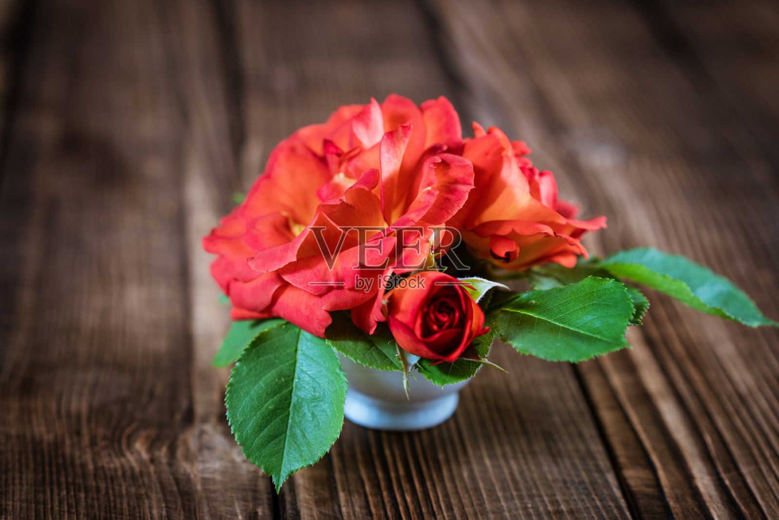 木背景上的花瓶里的一束小红玫瑰照片摄影图片