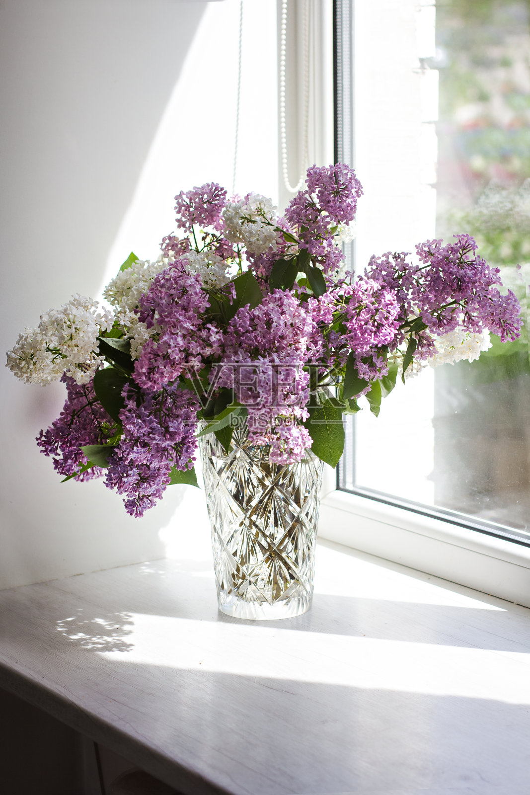 窗户上插着一束紫丁香的花瓶。照片摄影图片
