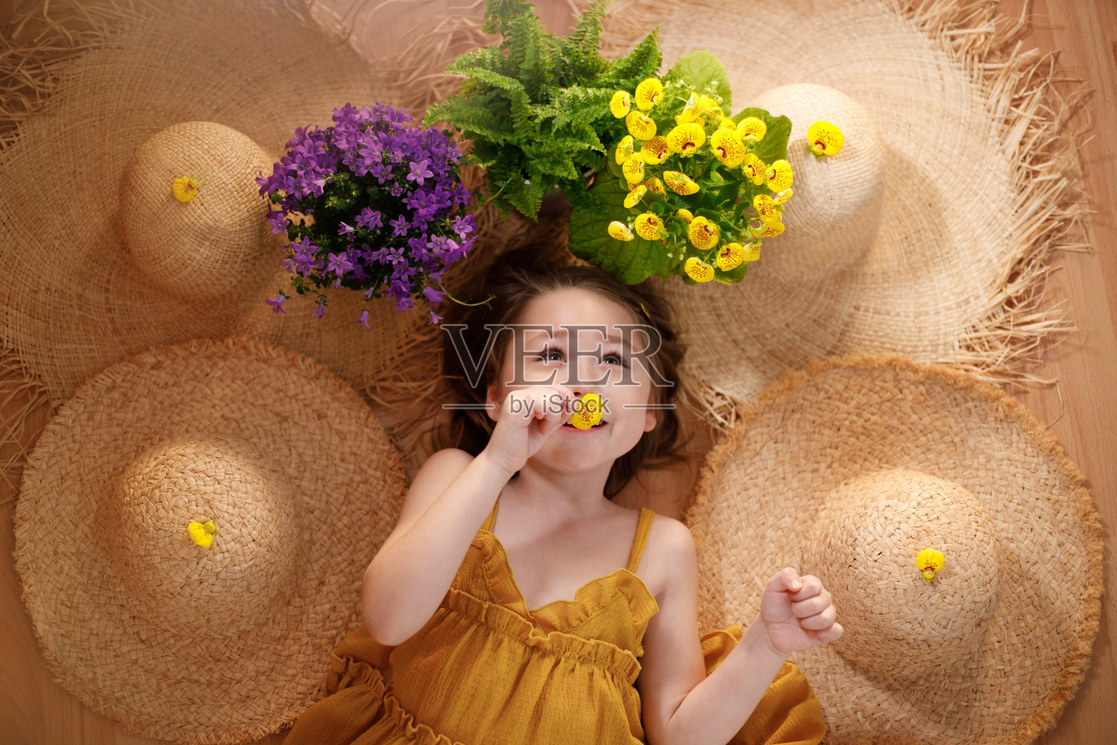 夏天和旅行的感觉，小女孩躺在花和草帽的背景照片摄影图片