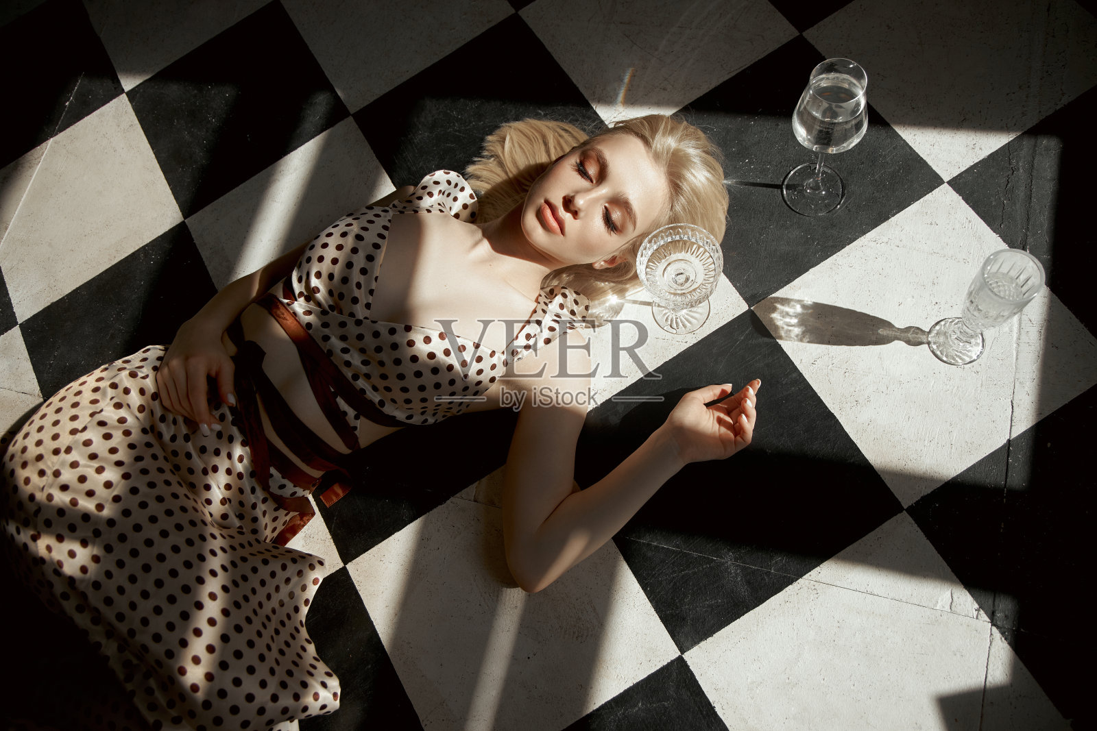 女人手里拿着酒杯躺在地板上，一个老内饰，看起来浪漫的金发女孩。女人身上的窗影照片摄影图片