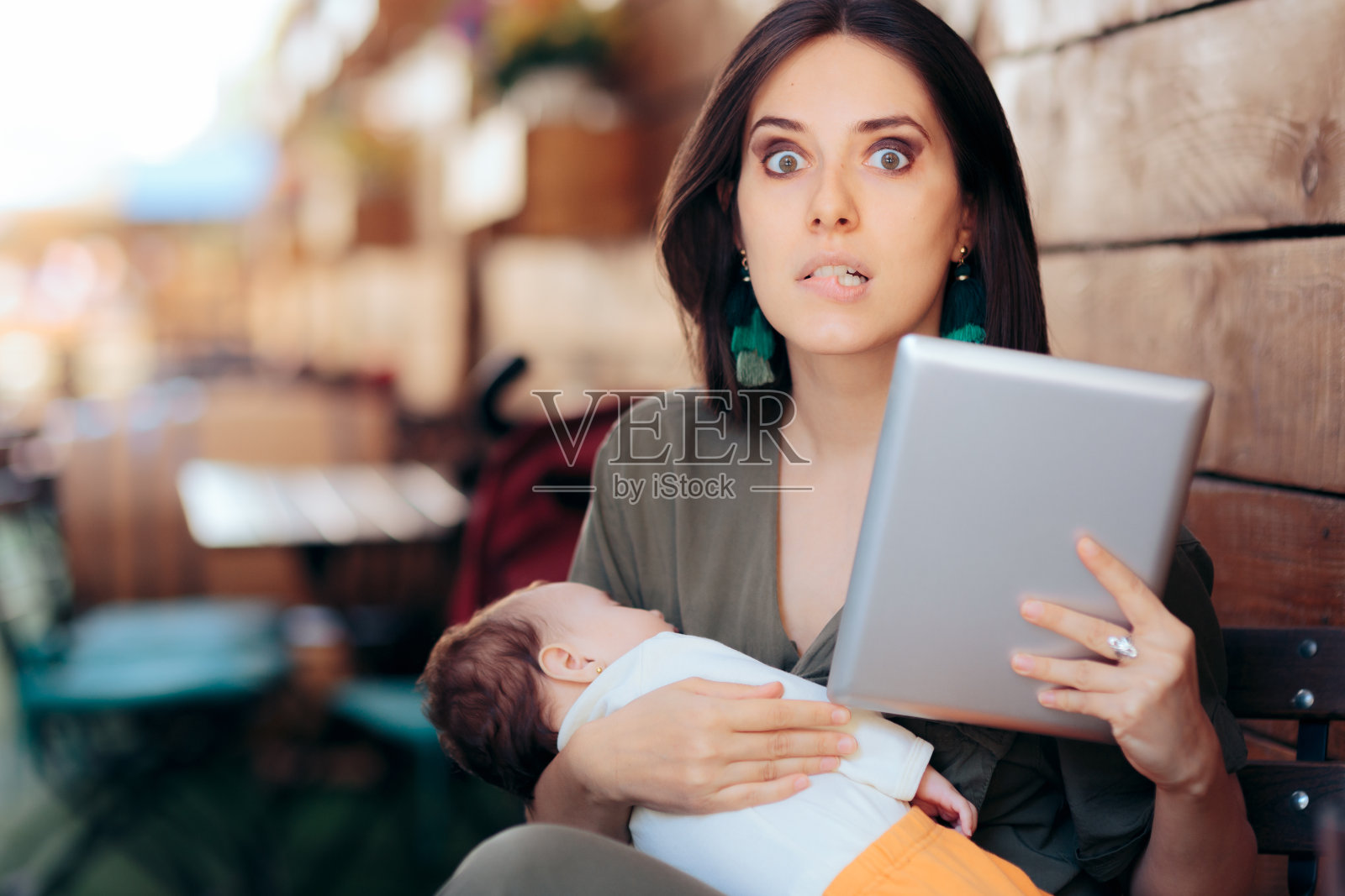 忙碌的妈妈抱着熟睡的婴儿远程工作照片摄影图片