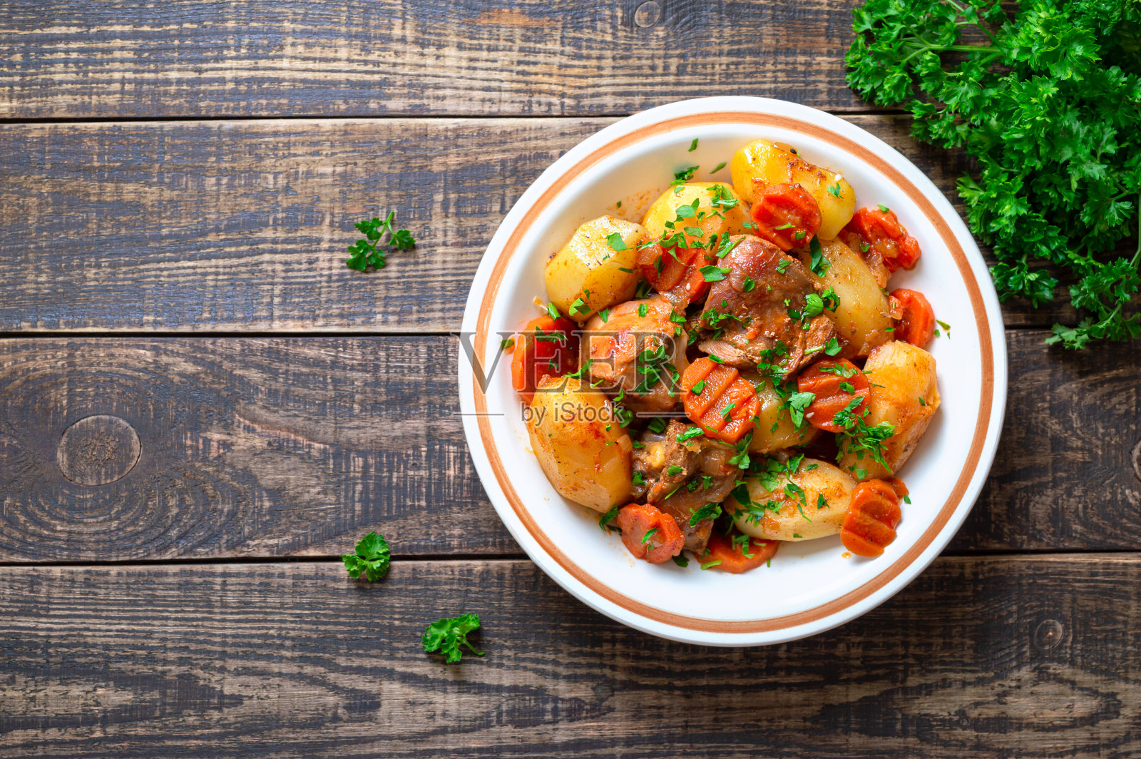 烤火鸡，土豆，胡萝卜和新鲜的欧芹放在一个碗里，木质的背景。前视图。本空间照片摄影图片