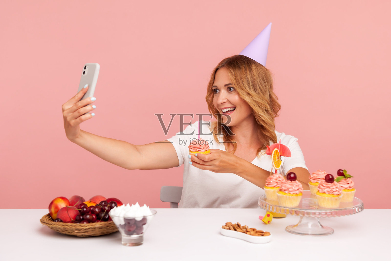 微笑的金发女子在网上和粉丝一起庆祝生日，直播，在镜头前展示美味的蛋糕和蜡烛，看起来很开心。照片摄影图片