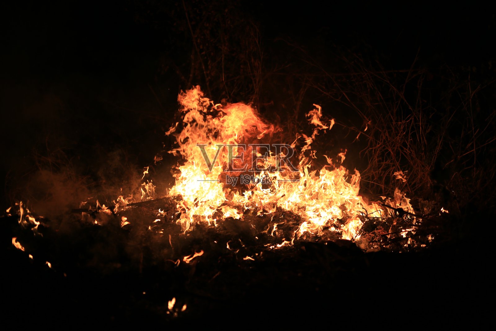 火焰燃烧着黑暗背景上的干草。照片摄影图片