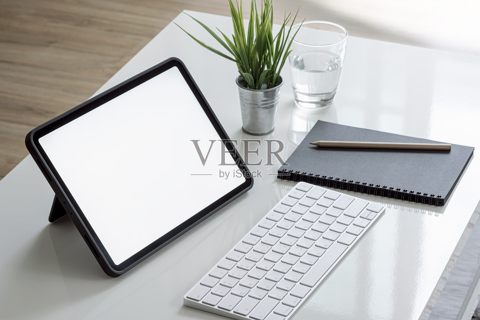 客厅白色木桌上的黑屏键盘平板电脑。照片摄影图片