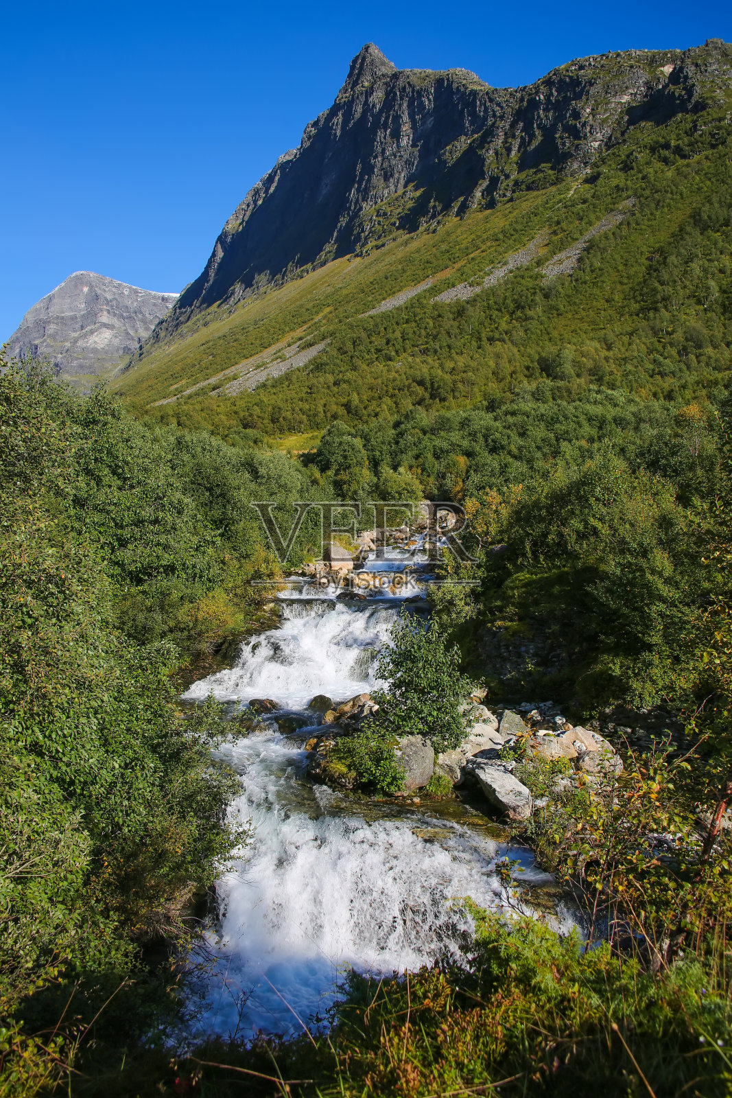美丽的景色从Fosseråsa徒步旅行路径Storsæterfossen瀑布与山脉，和山谷景观的背景。挪威Geiranger峡湾附近。夏日，湛蓝的天空笼罩着美景。照片摄影图片