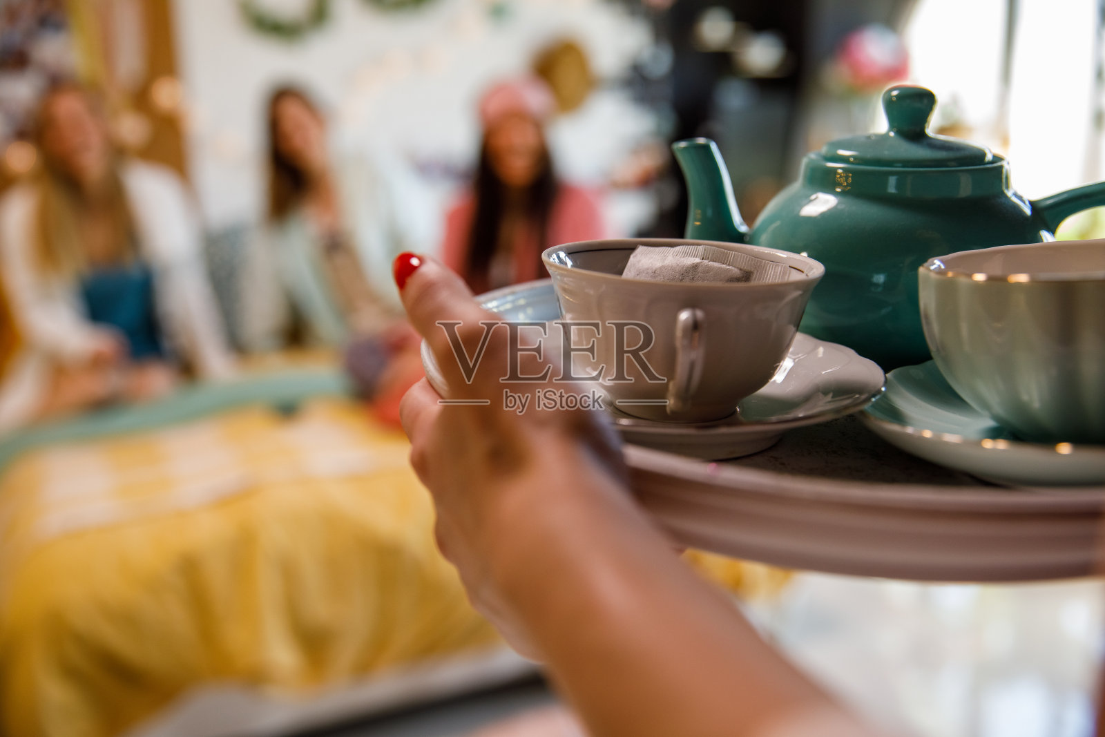 一个女人拿着一个盛着茶的托盘给她的朋友照片摄影图片