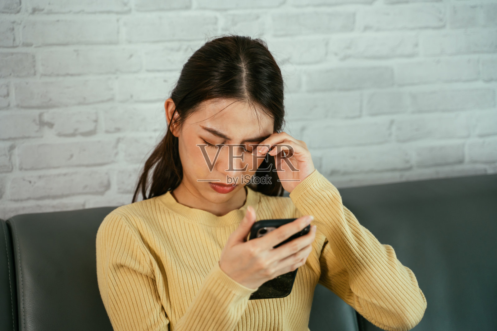 女人一边用手机一边揉眼睛照片摄影图片