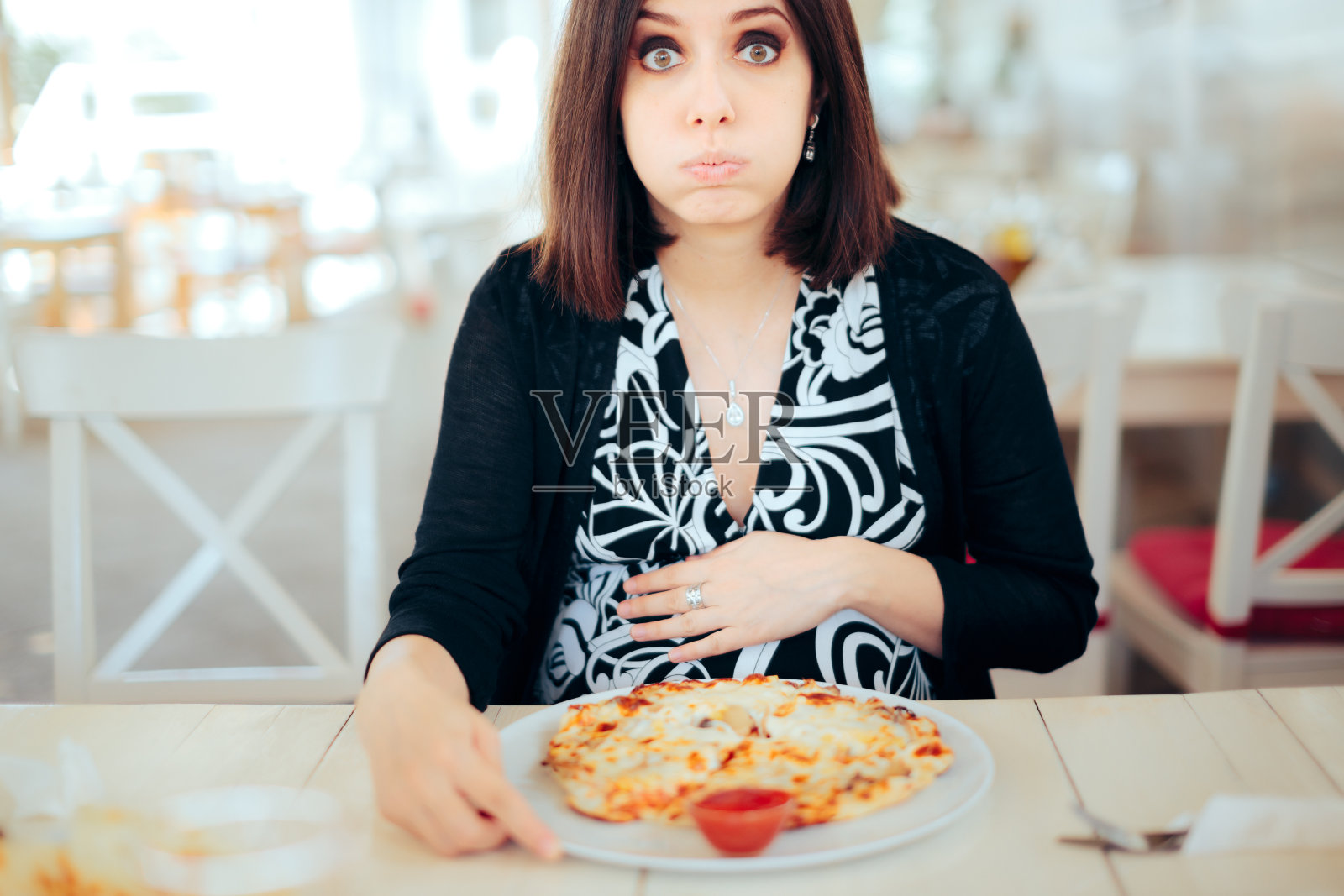 不开心的恶心孕妇试图吃披萨照片摄影图片