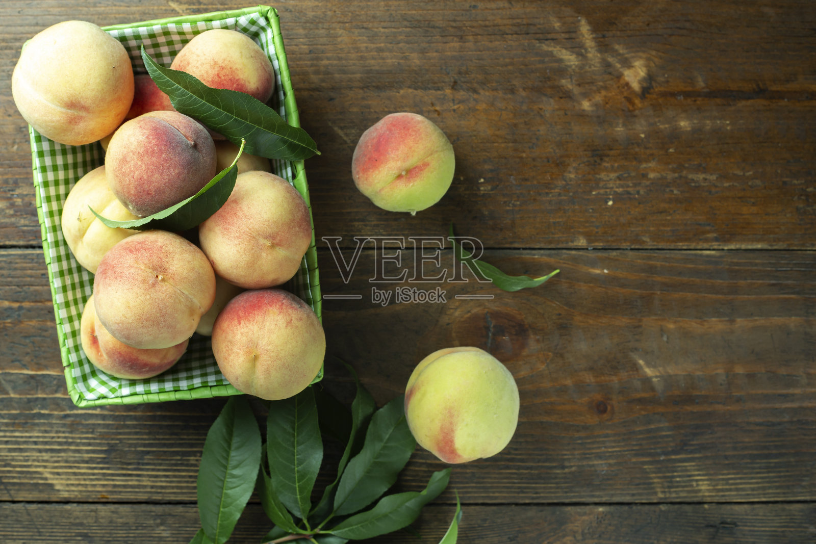 成熟的桃子在篮子里，木制的背景。自家菜园里的收获。照片摄影图片
