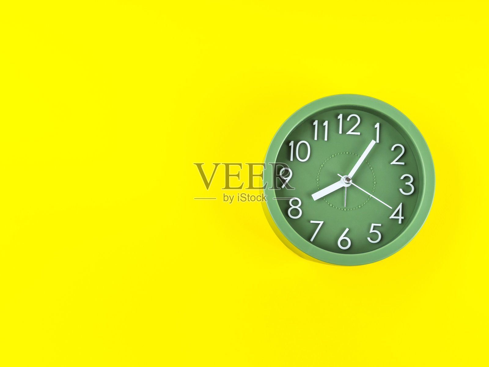 绿色闹钟，醒目的黄色背景。时间概念照片摄影图片