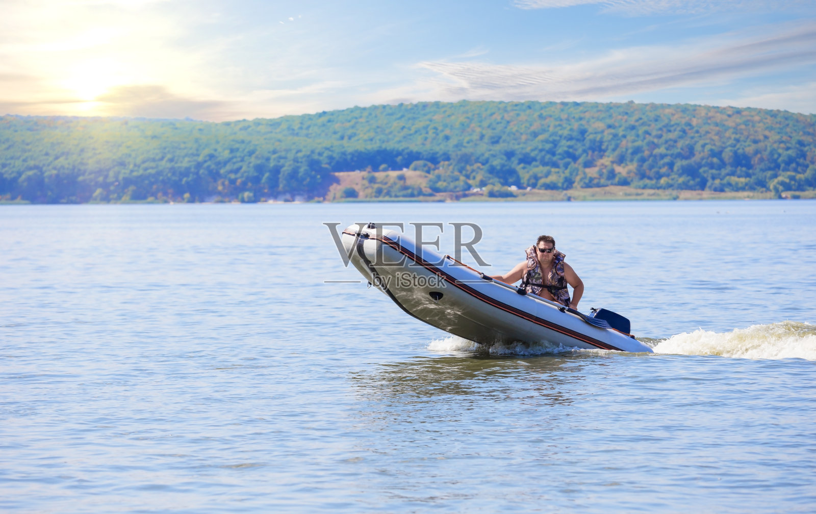 在阳光明媚的日子里，一艘橡胶摩托艇在水上行驶照片摄影图片