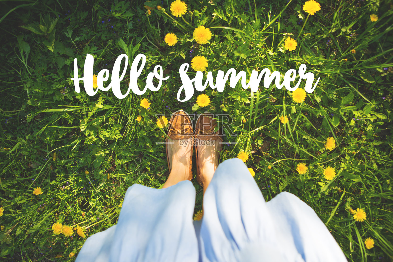 一个女人的脚踩在绿草和黄花上，题写着你好夏天照片摄影图片