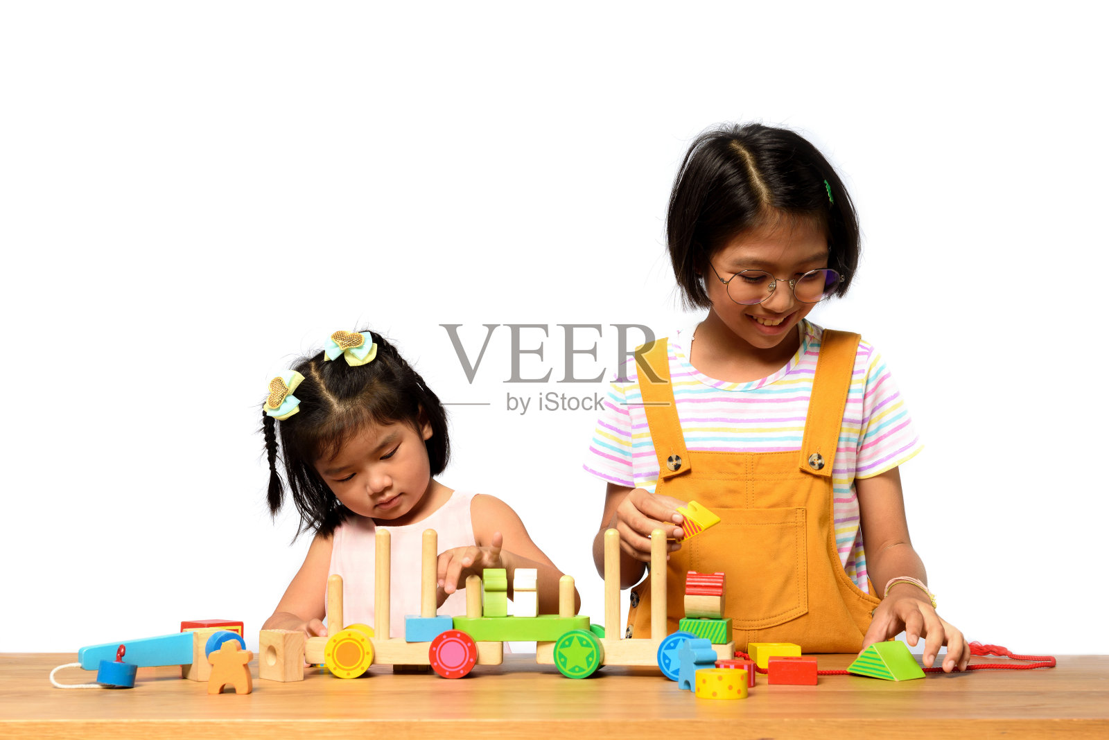 亚洲两姐妹的孩子一起在一张白色背景的木桌上玩耍。儿童技能，儿童角色与出生顺序，儿童发展概念照片摄影图片
