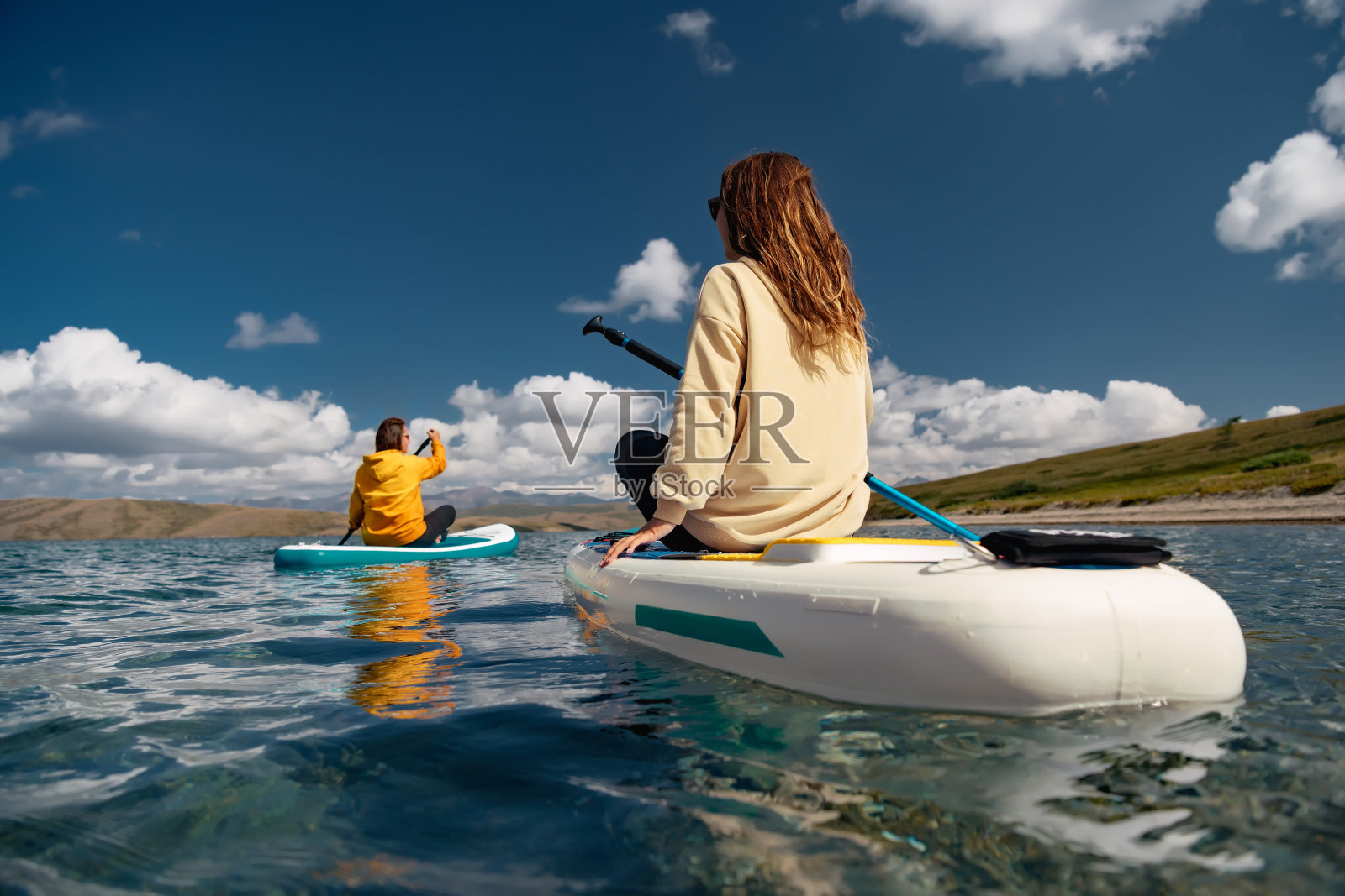 两个女孩在山湖的桨板旁散步照片摄影图片