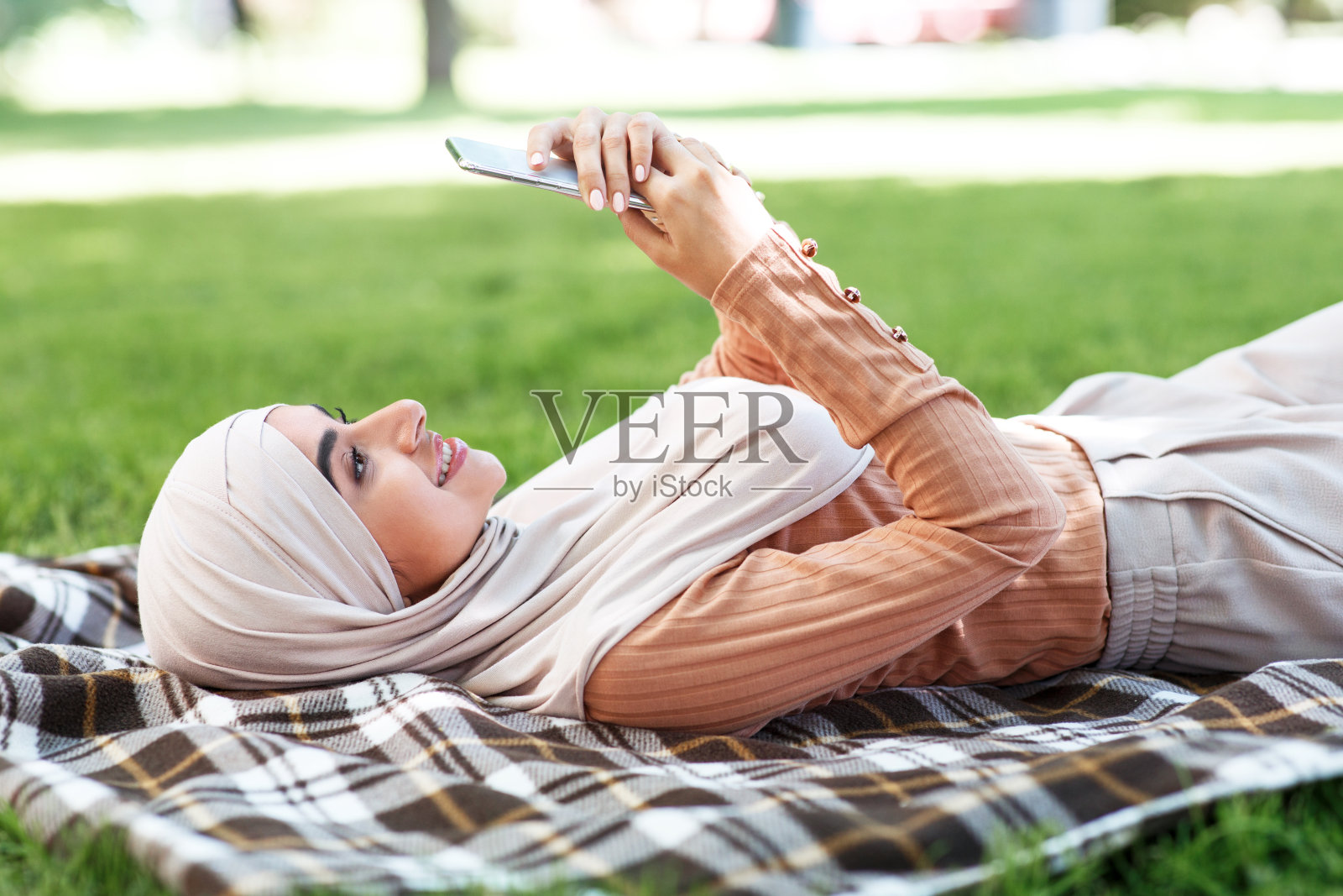 快乐的年轻阿拉伯妇女戴着头巾，打字，上网和社交网络照片摄影图片