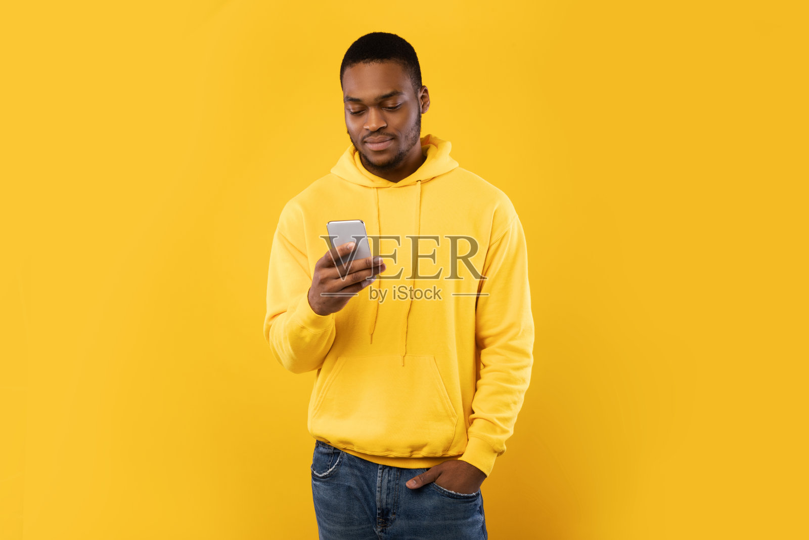非洲裔美国人使用智能手机滚动新闻，黄色工作室背景照片摄影图片