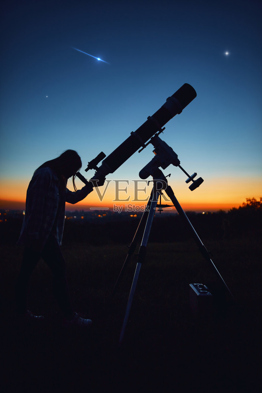 一个女人的剪影，望远镜和星空下的乡村。照片摄影图片