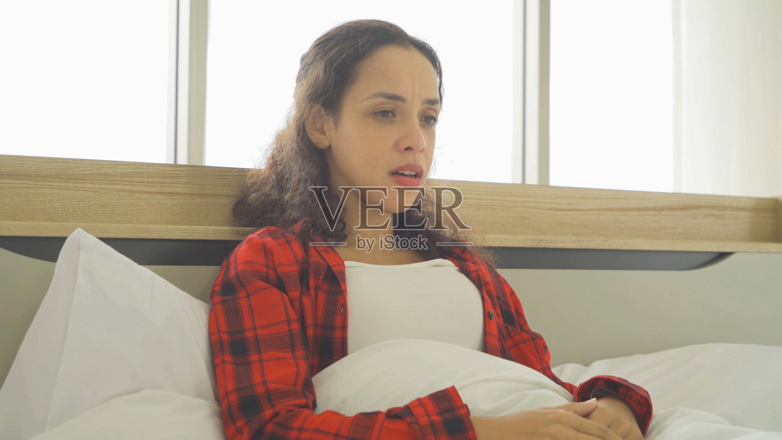 抑郁孤独悲伤情绪化的商业拉丁女人被解雇，哭泣。清晨坐在家里卧室的床上。隔离的生活方式。不快乐的生活。照片摄影图片