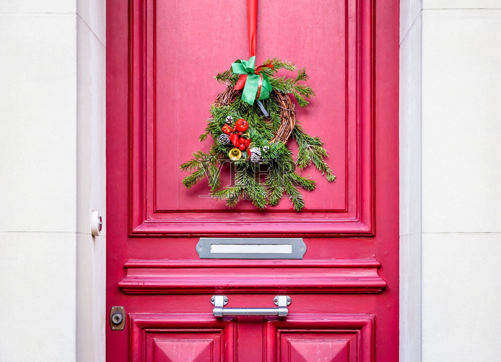 挂在红色大门上的圣诞花冠。照片摄影图片