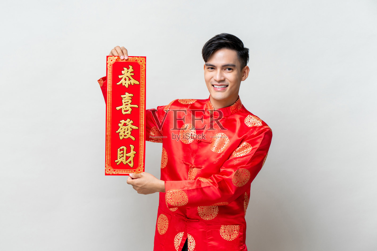 英俊微笑的亚洲男子显示红色标签与文字的意思是，可能你获得更大的财富在孤立的工作室浅灰色背景的中国新年概念照片摄影图片