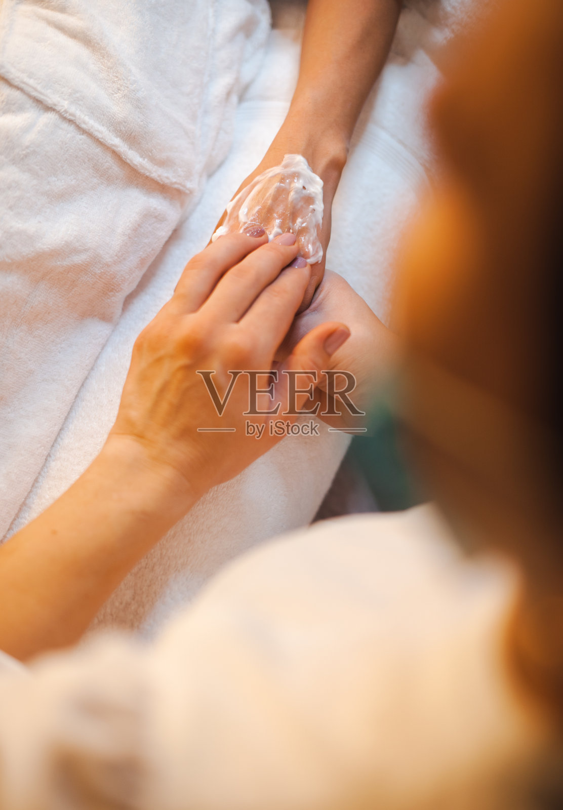 美容师在病人手上涂治疗霜。在美容水疗沙龙做手部护理。健康的生活方式。卫生保健。照片摄影图片