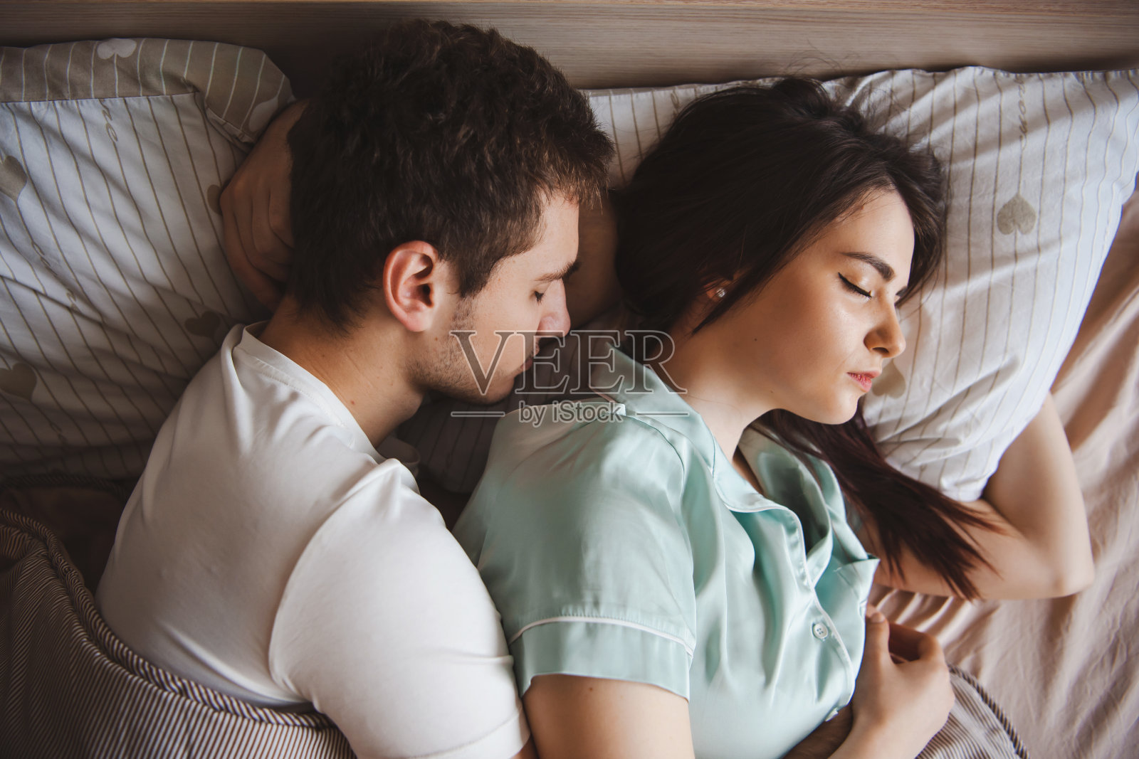 一对年轻夫妇在周末早上拥抱着睡觉的俯视图。情侣夫妻照片摄影图片