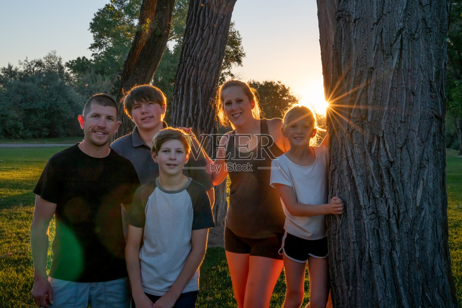 户外背光阳光日落肖像年轻英俊的白人家庭在一个美丽的公园照片摄影图片